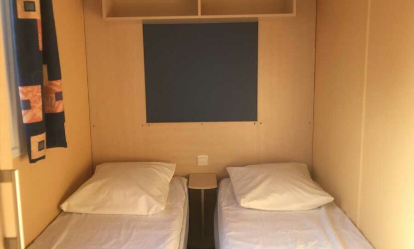 Deux lits simples dans une chambre d'un mobil-home au camping de contrexeville