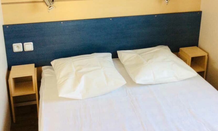 Un lit double dans une chambre d'un mobil-home au camping de contrexeville
